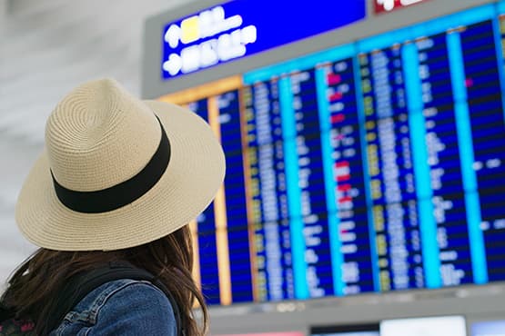 Voyageuse devant les panneaux aéroportuaires avant son taxi réservé